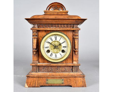 An Edwardian eight day mantle clock, the oak case with column design, flanking dial with black Roman numerals, German movemen