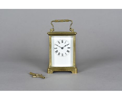 A brass carriage time piece, with white face, roman numerals, bracket feet, 14 cm high (key)