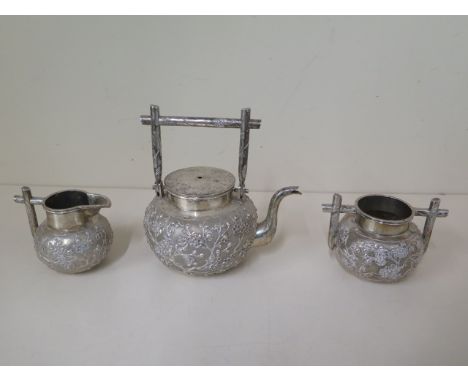 A Chinese silver three piece embossed tea set by Wang Hing marked WH90, the teapot with folding handle measuring 16cm with ha