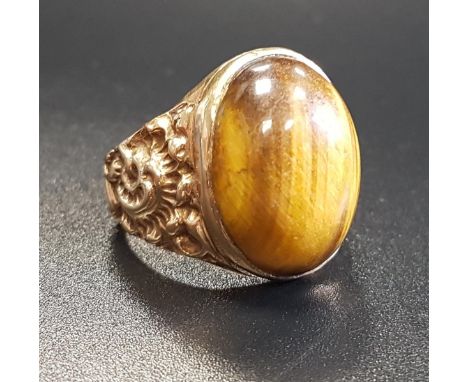 TIGER'S EYE DRESS RINGthe central oval cabochon tiger's eye flanked by relief scroll decorated shoulders, in nine carat gold,