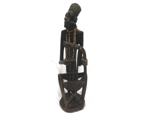 SIGNED CARVED AFRICAN WOODEN FIGUREof a story teller playing a three string Bolon seated on a stool, signed R. Katumba, 135cm