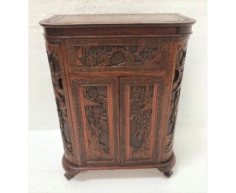 CHINESE CARVED TEAK DRINKS CABINETwith profuse carved decoration overall, the shaped lift up lid revealing a pair of doors op
