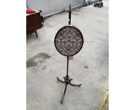 A 19TH CENTURY MAHOGANY OVAL POLE SCREEN ON TRIPOD BASE WITH BRASS BALL FEET