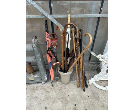 A SMALL STICK STAND AND AN ASSORTMENT OF WALKING STICKS AND UMBRELLAS TO INCLUDE A SHOOTING STICK ETC