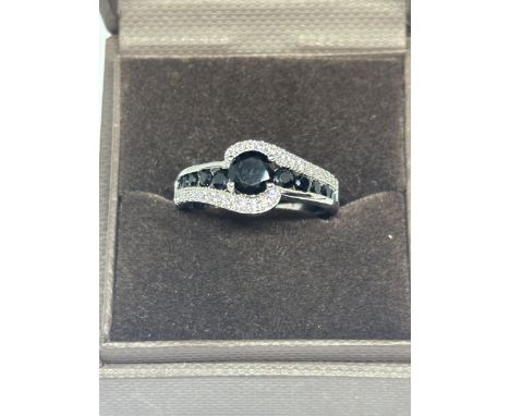 A SILVER DRESS RING WITH CLEAR AND BLACK STONES ON A TWIST SIZE R/S IN A PRESENTATION BOX