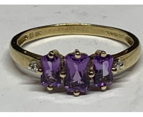 A 9 CARAT YELLOW GOLD RING WITH THREE IN LINE AMETHYST SIZE R/S