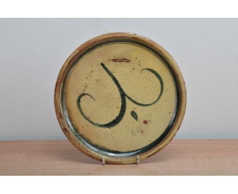 Joe Finch (British b.1947), for Winchcombe pottery, a studio pottery earthenware slipware plate, a green scroll design, impre
