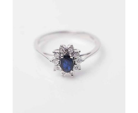 SAPPHIRE AND DIAMOND CLUSTER RING
with a central oval sapphire, surrounded by brilliant cut diamonds, in eighteen carat white