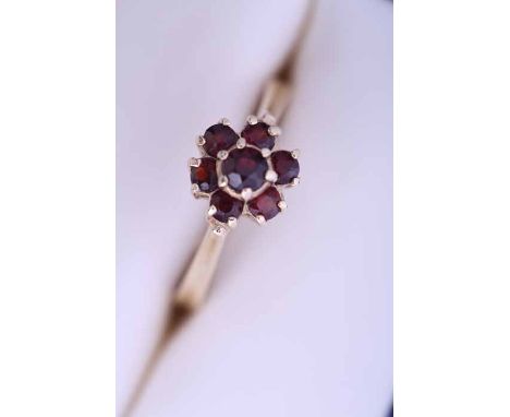 FOURTEEN CARAT GOLD GARNET CLUSTER RING
the bezel of floral form, set with seven round garnets,  marked for fourteen carat go