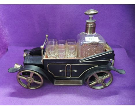 A decanter and six shot glass set in a model vintage car musical box