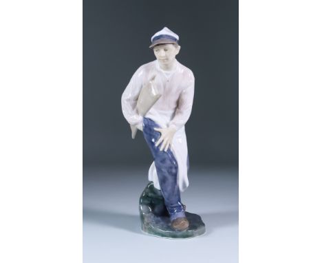 A Royal Copenhagen Porcelain Figure of a Butcher's Boy, Model No. 1660, designed by Christian Ludwig Thomsen (1860-1921), pai