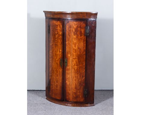 An 18th Century Oak Bow Front Hanging Corner Cupboard, inlaid with mahogany bandings enclosed by a pair of doors, 26ins wide 