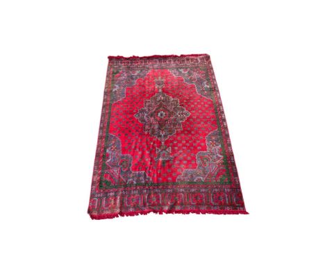 An Oushak carpet, 20th century, with central lozenge shaped medallion in green and blues on a red ground with repeating star 