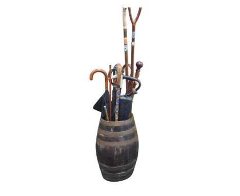 An oak brass bound barrel pattern stick stand, 58cms high; together with a quantity of sticks and umbrellas, an Uppingham swa