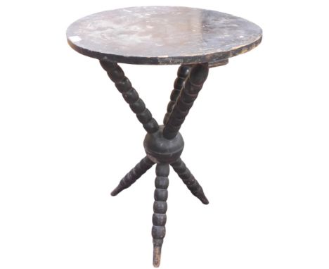 A 19th century stained pine cricket style occasional table with crossed bobbin turned supports, 69cm high x 51cm diameter Con