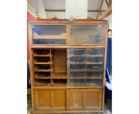 A large light oak habidashery cabinet with many pull out drawers and lift up glass doors, 66 1/2" w x 84" h x 21" d.