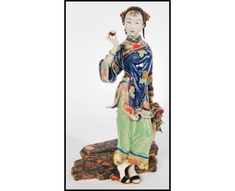 A Chinese ceramic figurine of a maiden seated having hand detailed floral motifs with character marks and calligraphy script 