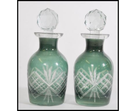 A pair of two small Victorian green cut glass perfume bottles with a cut glass finial stoppers. Measures 13 cm high.