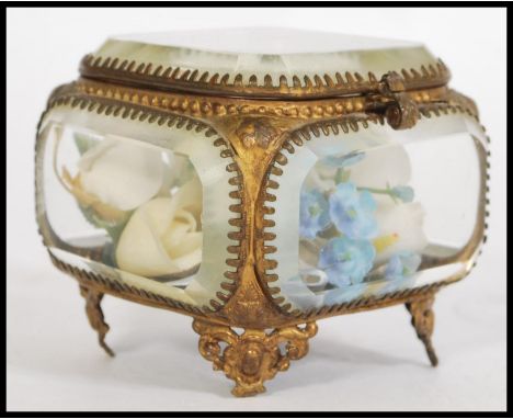A 20th century brass casket trinket box having bevelled glass panels, raised on four scroll work feet with a hinged lid and a