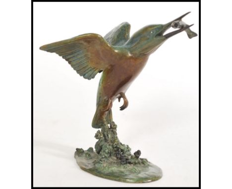 A cold cast bronze figurine of a Kingfisher in flight carrying a fish in its beak rising from water, signed P. A. Northcroft 