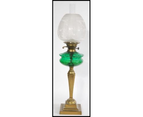 A Victorian brass and green glass oil lamp of neo-classical form having acid etched globe shade and flue with green glass res