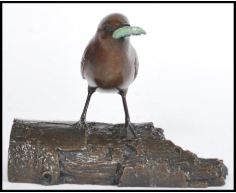 A cold cast bronze figurine of a wren perched on a log with a green grub in its beak by Eddie Hallam, signed by artist to the