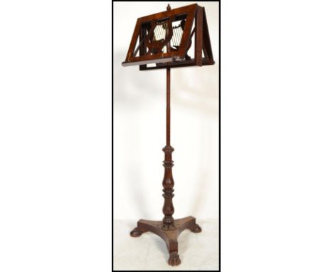 A 19th century rosewood and mahogany duet music stand raised on tripod hairy paw feet with carved harp decoration.