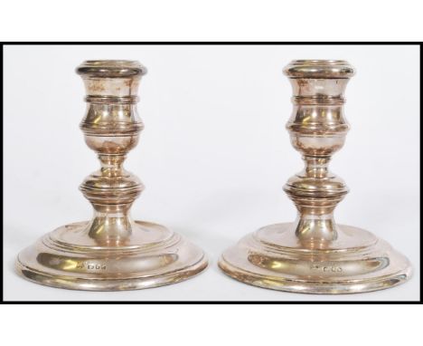 A pair of silver hallmarked candlesticks raised on filled stepped circular bases with knopped stems. Hallmarked for London da