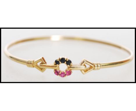 A hallmarked 9ct gold ruby and sapphire set bangle bracelet with a hook clasp. Hallmarked London. Weight 4.9 g.