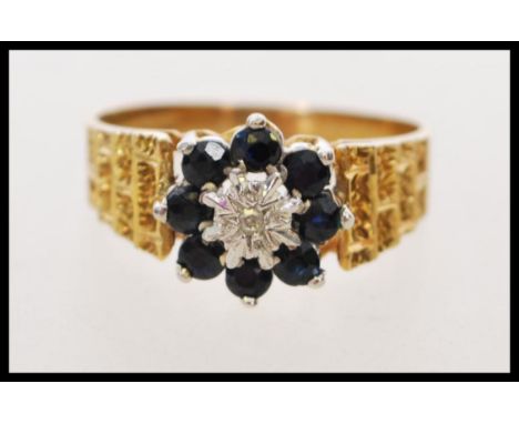 A hallmarked 9ct gold retro sapphire and diamond cluster ring having brick work engraving to the shoulders. Hallmarked Birmin