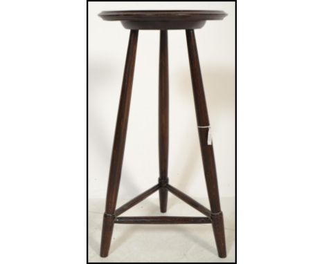 An early 20th century arts and crafts circular topped side/ lamp table raised on turned legs with spade feet united by periph