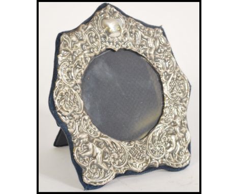 A hallmarked 20th century silver picture frame having a scrolled design with cherub puttis and easel back. Hallmarked for Lon