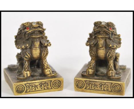 A pair of unusual brass Chinese temple / foo dog scroll weights. Each with brass plinth bases having character markings, each