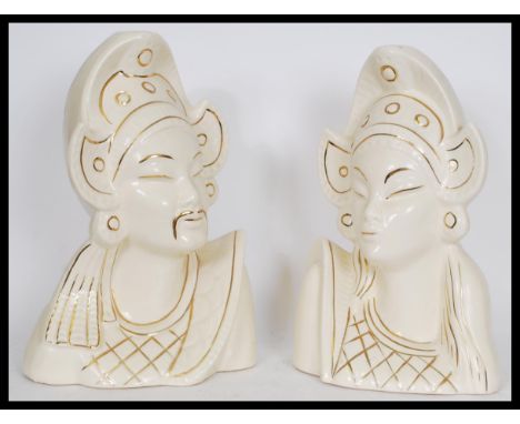 A pair of Asiatic white ceramic bust figures depicting a man and a woman in traditional dress with gold detailing. Measures: 