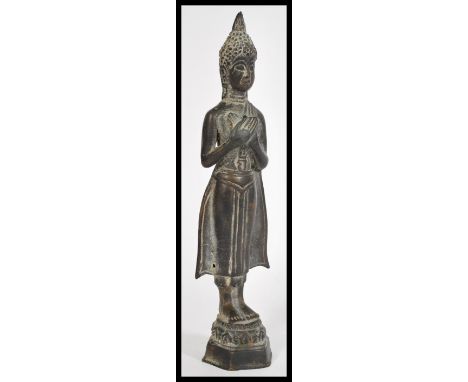 A 19th century Oriental bronze figurine of a deity raised on hexagonal pedestal base with headdress and hands crossed.&nbsp;m