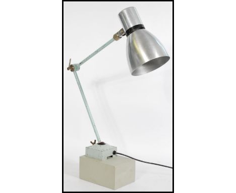 A vintage retro 20th century industrial work desk lamp raised on a wooden base with square metal base, adjustable arm and con