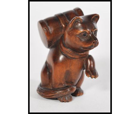 A 20th century Japanese wooden netsuke in the form of a cat sat on it's hind legs with it's front paws up. Approx 5cm tall.
