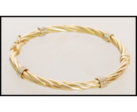 A hallmarked 9ct gold bangle of twisted form with a hinge opening. Weight 8.3g. Measures 8 cm diameter.