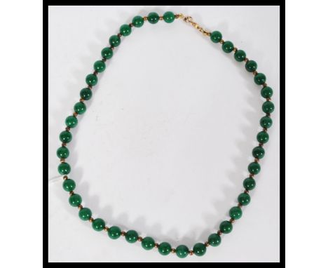 A Chinese green jade bead necklace having small gilt bead spacers with yellow metal claw clasp.&nbsp;measures: 23cm long.