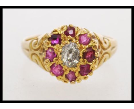 An 18ct gold ruby and diamond ring set with a central oval old cut diamond (approx 6mm x 4mm) surrounded by a halo of rubies 