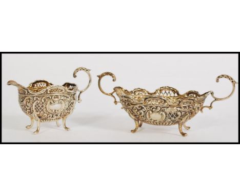 A silver hallmarked twin scroll handled rococo and fret pierced sugar bowl raised on scroll feet together with a matching cre
