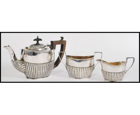 An early 20th century silver hallmarked three piece tea service in the boat pattern by William Aitken having half reeded bodi