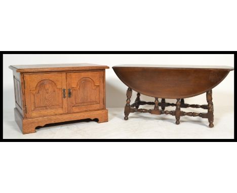 An Ercol 20th century dark beech and elm wood drop leaf coffee table being raised on bobbin turned legs together with a Brigh