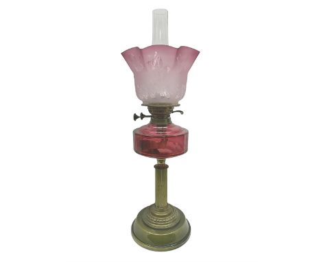 Victorian oil lamp, with brass corinthian column, cranberry glass reservoir and stepped ceramic base, H66cm