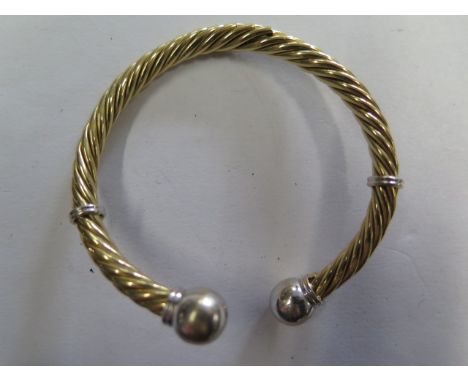 A yellow gold and white metal sprung coiled bangle, tests to approx 18ct, approx 23 grams, splitting to coils and some small 