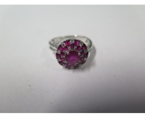 An 18ct white gold diamond and ruby cluster ring; head approx 12mm diameter, marked 750, ring size L, approx 3.5gs. In good c