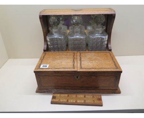 An oak three bottle tantalus games box with cribbage board, no makers name, all bottles are chipped 