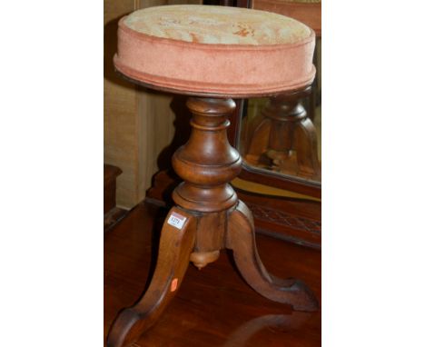 A Victorian mahogany piano stool having a tapestry upholstered revolving top