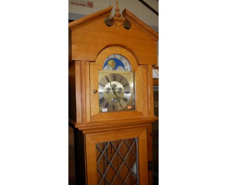 A contemporary light oak longcase clock, having moonphase arched dial, with three train movement, lead glazed trunk door, wit