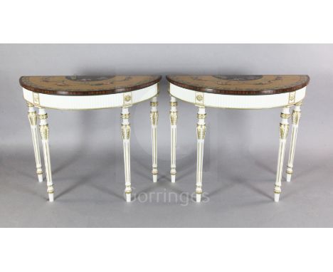 A pair of Adam revival painted and parcel gilt demi lune console tables, with rosewood banded maple tops decorated with flora